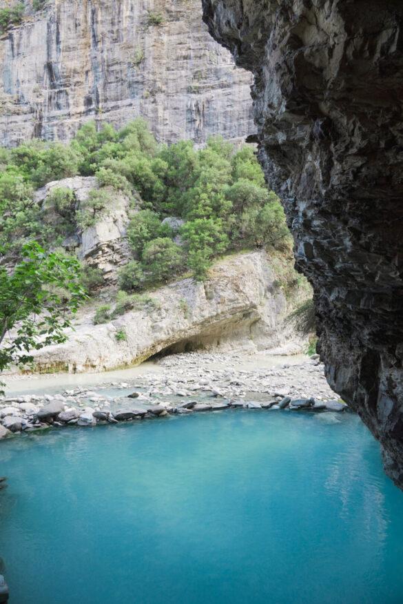 Blaue Schwefelquelle vor steiler Felswand bei Bënjë in Albanien