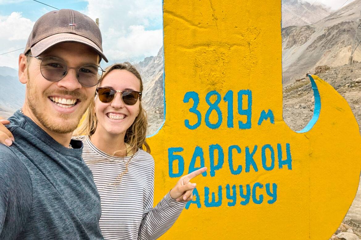 Junges Paar vor einer kirgisischen Passtafel