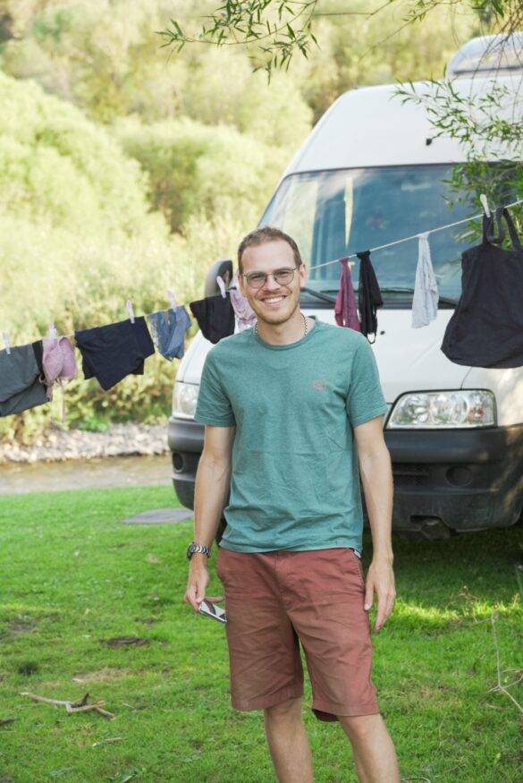 Junger Mann vor einem Camper und einer Wäscheleine.