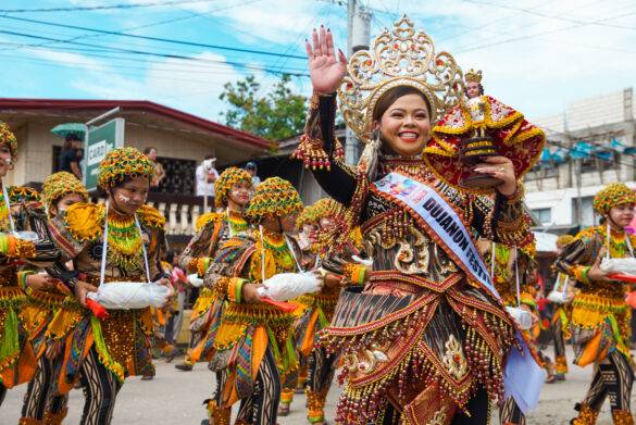 Winkende Frau in traditionellem Gewand am Karnevalumzug auf den Philippinen
