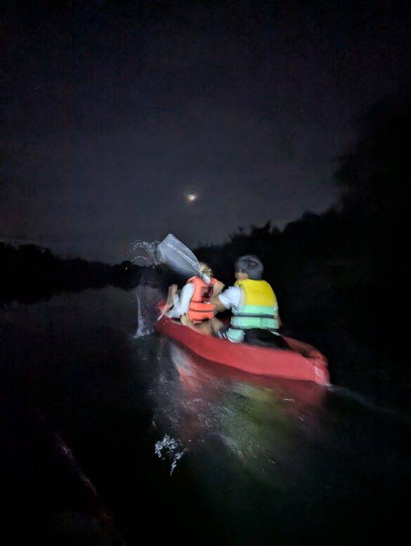 Zwei Menschen in einem Kayak auf dem Wasser umgeben von nächtlicher Dunkelheit auf den Philippinen.