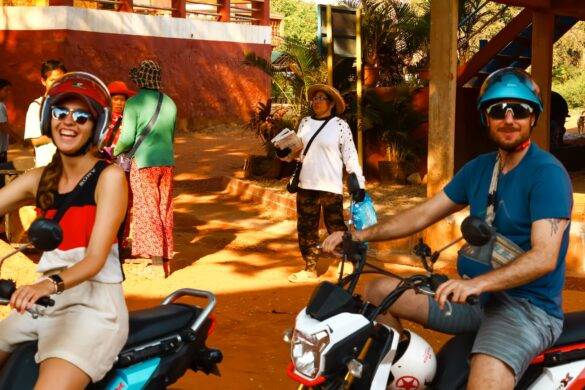 Zwei lachende Menschen auf Rollern in Kambodscha.